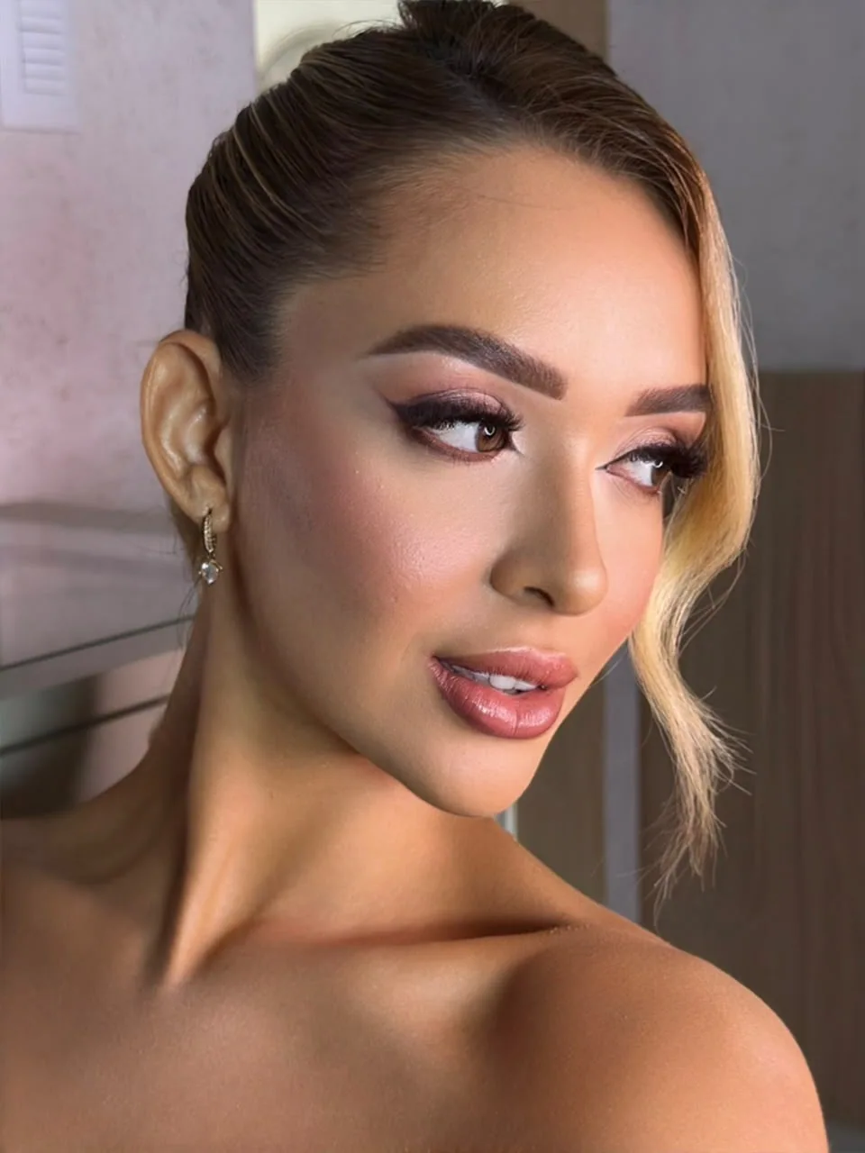 Maquiagem com olhos esfumados em tons rosados e lábios brilhantes.