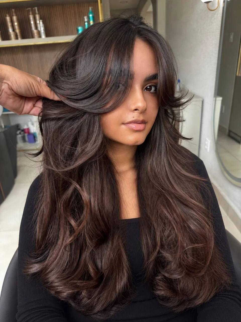 Cabelo castanho longo com camadas, volume e pontas modeladas para fora junto ao rosto.